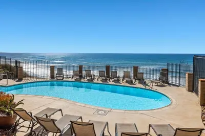 a swimming pool with chairs and the ocean in the background at A Shore Thing! - DMST21 in Solana Beach