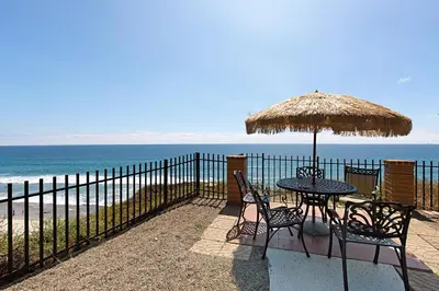 a table and chairs with an umbrella and the beach at A Shore Thing! - DMST21 in Solana Beach