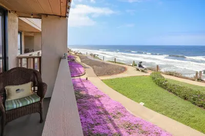 a porch with purple flowers and a chair and the ocean at Pacific Perch - SUR115S in Solana Beach