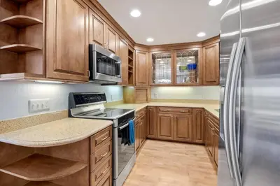 a kitchen with wooden cabinets and a stainless steel refrigerator at Ocean Dreams - SBTC145 in Solana Beach