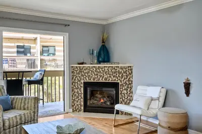 a living room with a fireplace and a chair at Ocean Dreams - SBTC145 in Solana Beach