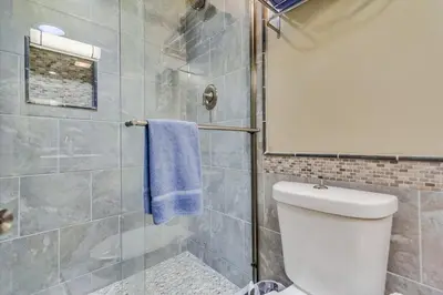 a bathroom with a shower with a toilet and a blue towel at Bare Feet &Salty Hair-DMBC141S in Solana Beach