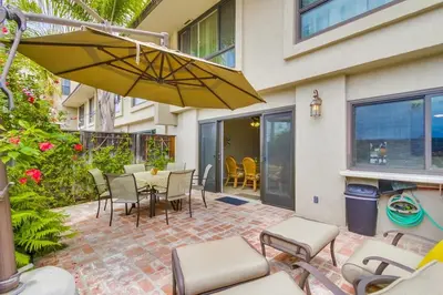 a patio with a table and chairs and an umbrella at Bare Feet &Salty Hair-DMBC141S in Solana Beach
