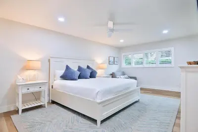 a white bedroom with a white bed and blue pillows at Cast-a-Waves - SUR29 in Solana Beach