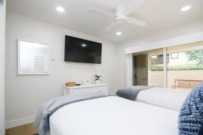 a bedroom with two beds and a flat screen tv at Cast-a-Waves - SUR29 in Solana Beach