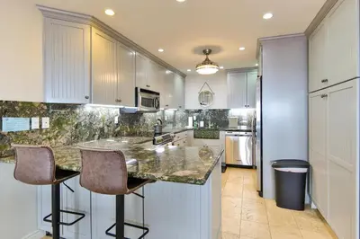 a kitchen with white cabinets and a counter with bar stools at Barefoot Oasis - SUR127 in Solana Beach