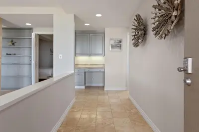 a hallway with a door leading to a kitchen at Barefoot Oasis - SUR127 in Solana Beach