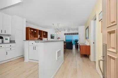 an open kitchen and dining room with white cabinets at Once Upon A Tide - SBTC312 in Solana Beach