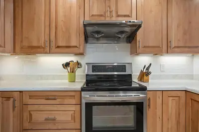 a kitchen with a stove and wooden cabinets at Shore O'Clock - SBTC149 in Solana Beach