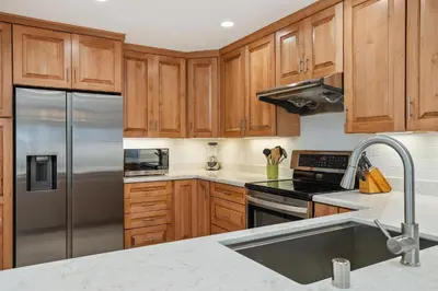 a kitchen with wooden cabinets and a stainless steel refrigerator at Shore O'Clock - SBTC149 in Solana Beach