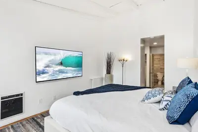 a bedroom with a white bed and a tv on the wall at Shore O'Clock - SBTC149 in Solana Beach