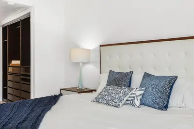 a bedroom with a white bed with blue pillows at Shore O'Clock - SBTC149 in Solana Beach