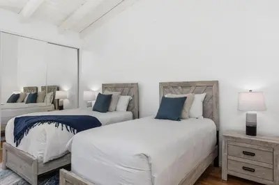 a white bedroom with two beds and a mirror at Shore O'Clock - SBTC149 in Solana Beach