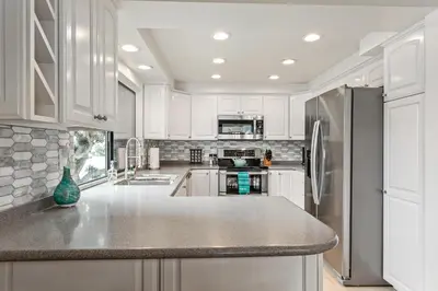 a kitchen with white cabinets and a stainless steel refrigerator at Drift Away - DMBC884 in Solana Beach
