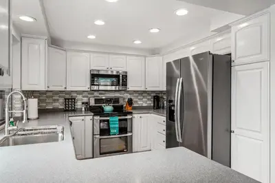a kitchen with white cabinets and a stainless steel refrigerator at Drift Away - DMBC884 in Solana Beach