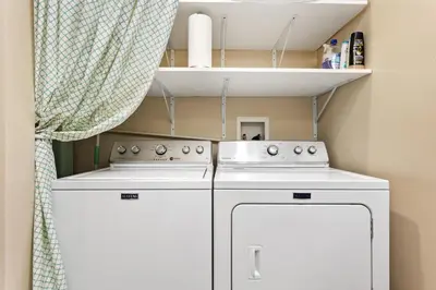 a small kitchen with two white appliances and a curtain at Beachfront Bliss - DMBC815 in Solana Beach