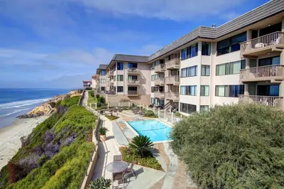an apartment building with a swimming pool next to the ocean at Beachfront Bliss - DMBC815 in Solana Beach