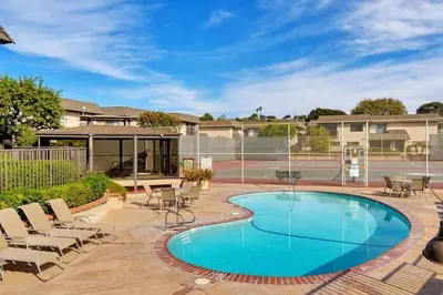 a swimming pool with chairs and a tennis court at Beachfront Bliss - DMBC815 in Solana Beach