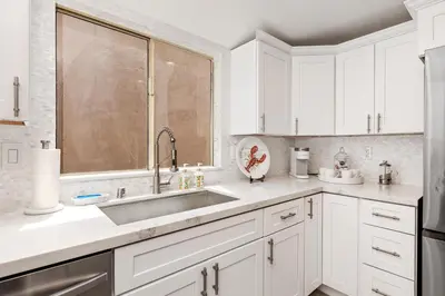 a kitchen with white cabinets and a sink at Solana Escape - SUR44 in Solana Beach