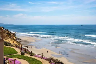 a beach with people walking on the sand and the ocean at Solana Escape - SUR44 in Solana Beach