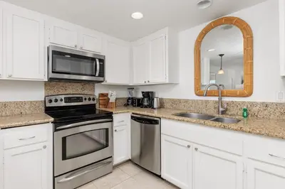 a kitchen with white cabinets and a sink and a microwave at Sunset Retreat - SUR105 in Solana Beach