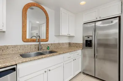 a kitchen with white cabinets and a stainless steel refrigerator at Sunset Retreat - SUR105 in Solana Beach