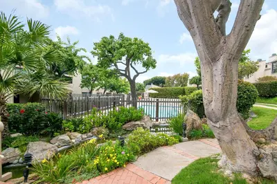 a garden with a fence and trees and flowers at Sunset Retreat - SUR105 in Solana Beach