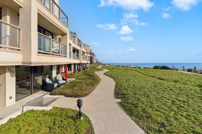 a walkway next to a building with the ocean in the background at Tide and True - SUR129S in Solana Beach