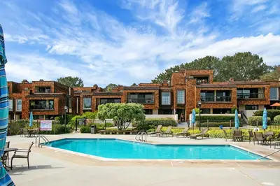 a resort pool with tables and chairs in front of a building at Mermaid's Lookout in San Diego