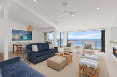 a living room with blue furniture and a view of the ocean at King of the Beach - SUR79 in Solana Beach