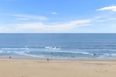 a beach with people walking on the sand and the ocean at King of the Beach - SUR79 in Solana Beach
