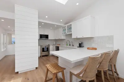 a kitchen with white cabinets and a counter with stools at King of the Beach - SUR79 in Solana Beach