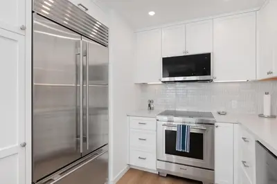 a kitchen with white cabinets and a stainless steel refrigerator at King of the Beach - SUR79 in Solana Beach