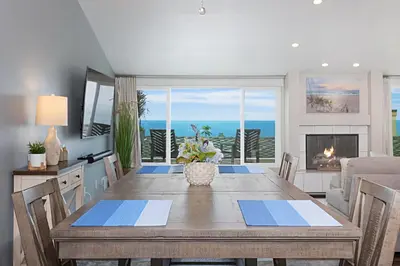 a dining room with a table and a view of the ocean at Coastal Retreat- SUR33 in Solana Beach