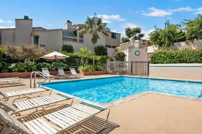 a swimming pool with lounge chairs next to a building at Coastal Retreat- SUR33 in Solana Beach