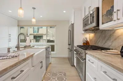 a kitchen with white cabinets and stainless steel appliances at Pacific Bliss - DMBC767 in Solana Beach