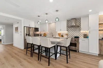 a kitchen with white cabinets and a table and chairs at Fairway Haven - CB2507 in Carlsbad