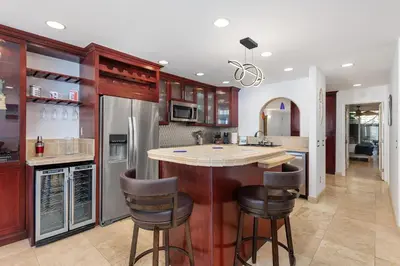 a kitchen with a island with bar stools at Whale Watch - DMST12 in Solana Beach