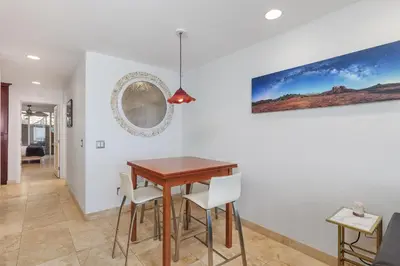 a dining room with a wooden table and white chairs at Whale Watch - DMST12 in Solana Beach