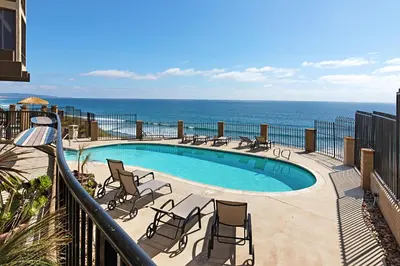 a swimming pool with chairs and the ocean in the background at Whale Watch - DMST12 in Solana Beach