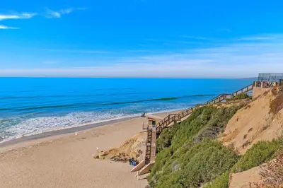a sandy beach with a staircase leading to the ocean at Whale Watch - DMST12 in Solana Beach
