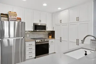 a kitchen with white cabinets and a stainless steel refrigerator at Aqua Horizon - SBTC112 in Solana Beach