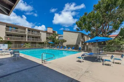 a swimming pool with chairs and a table and an umbrella at Aqua Horizon - SBTC112 in Solana Beach