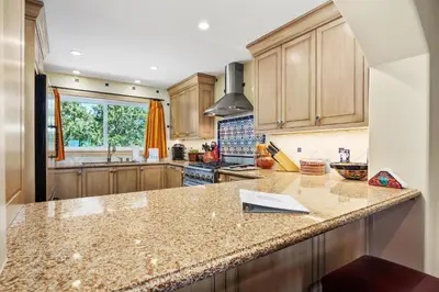 a kitchen with wooden cabinets and a granite counter top at Villa del Pacifico - SONG20 in Solana Beach
