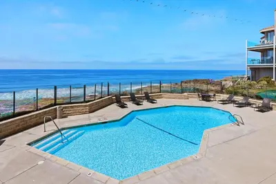 a swimming pool with chairs and the ocean in the background at Villa del Pacifico - SONG20 in Solana Beach