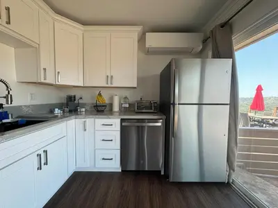 a kitchen with white cabinets and a stainless steel refrigerator at Serenity - Amazing Views & Modern Charm in La Mesa