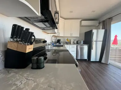 a kitchen with white cabinets and a stainless steel refrigerator at Serenity - Amazing Views & Modern Charm in La Mesa