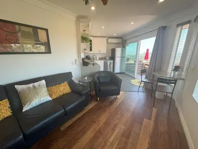 a living room with a black couch and a kitchen at Serenity - Amazing Views & Modern Charm in La Mesa