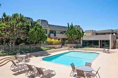 a swimming pool with chairs and a table next to a house at Beachy Keen & Cleen - DMBC148S in Solana Beach