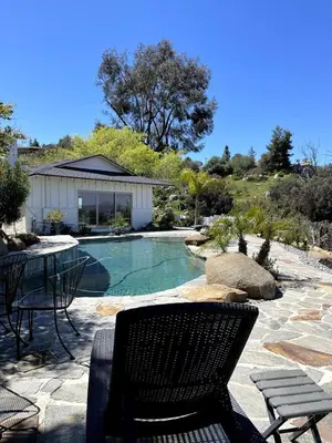 a patio with a table and chairs next to a pool at Avocado House in El Cajon